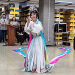 Presentación artística de baile realizada en un espacio de biblioteca con público observando la actividad